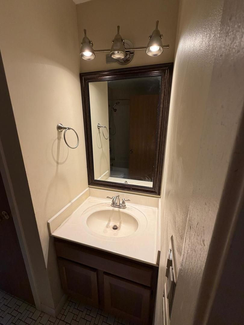 Bathroom vanity with an oval sink, dark wood cabinet, and large framed mirror.