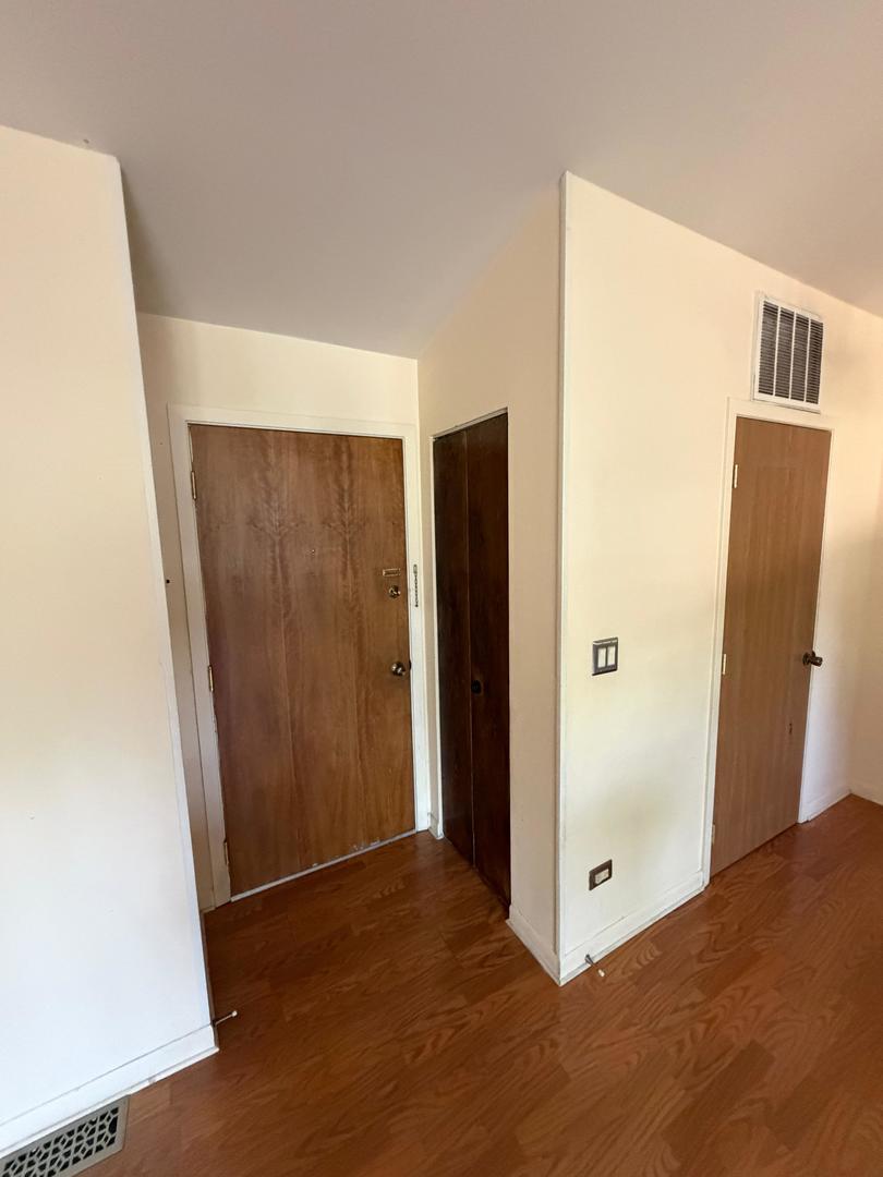 Apartment entry hall with wood flooring and a wooden front door beside two interior doors.