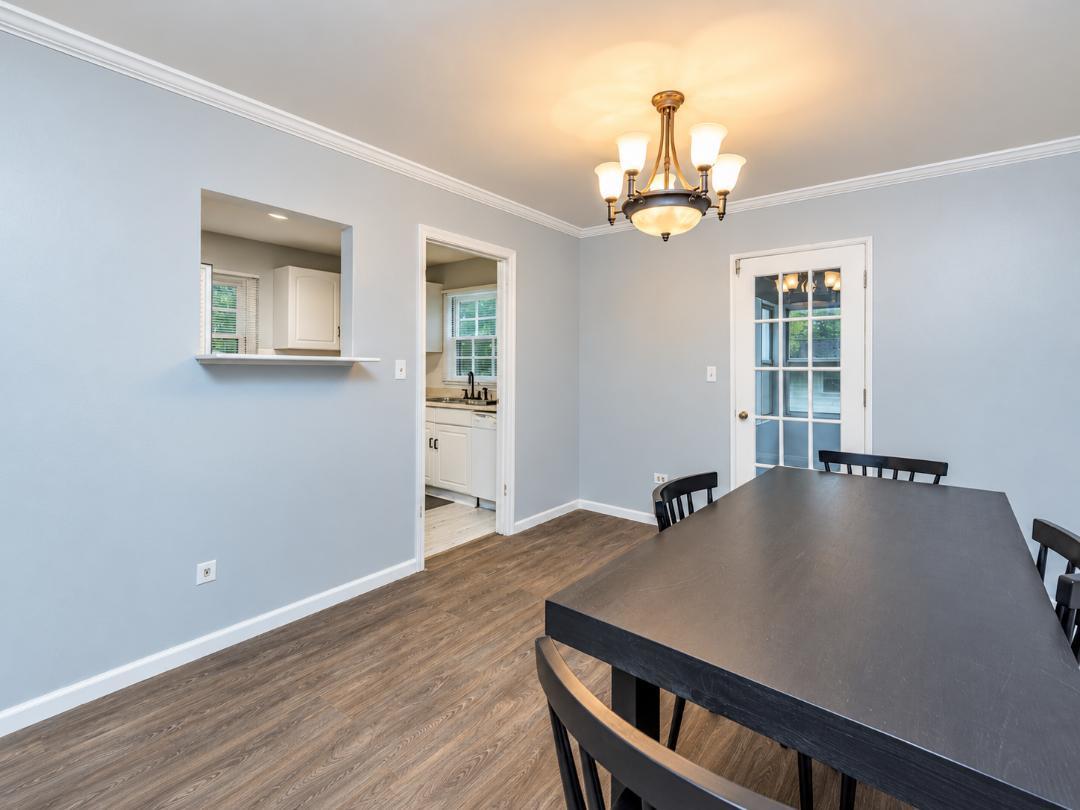 Dining room with a dark table, brass chandelier, and pass-through to the kitchen.