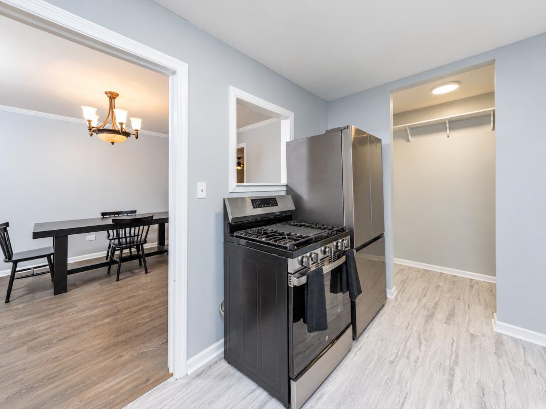 Kitchen with stainless-steel appliances and an adjoining dining area with a table and chairs.