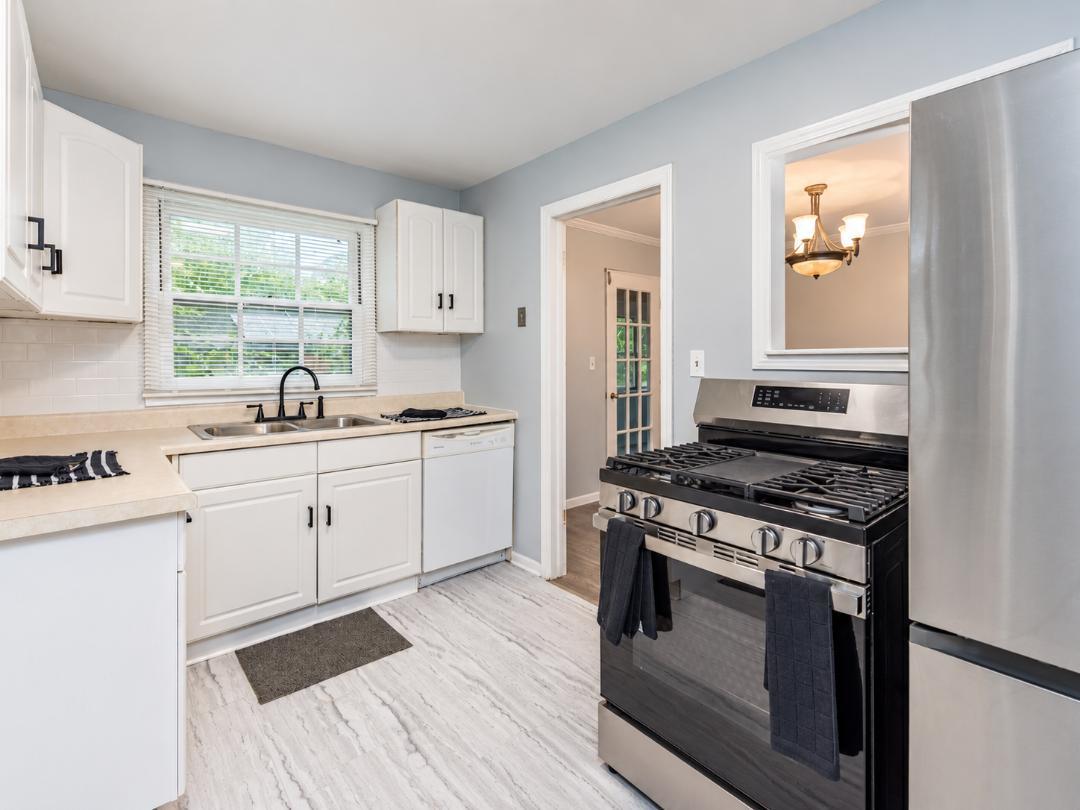 Kitchen with white cabinets, a window over the sink, and a large stainless steel gas range.