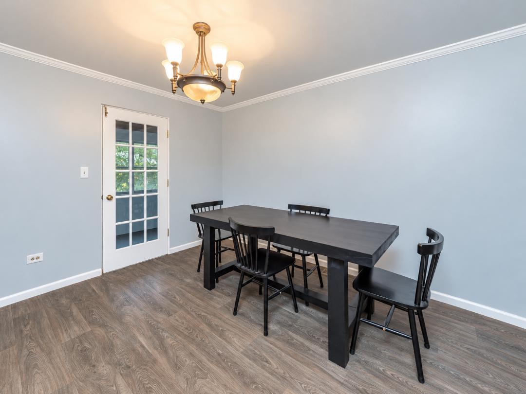 Dining room with a dark table and black chairs, beside a white glass-paneled door.