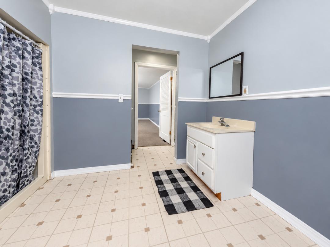 Bathroom with a white vanity, tiled floor, and patterned shower curtain.