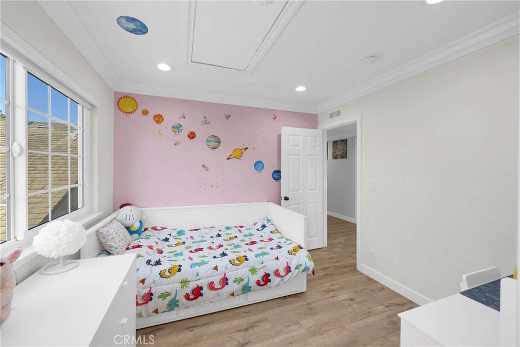 Child’s bedroom with colorful sea-creature bedding and a pink wall decorated with planets.