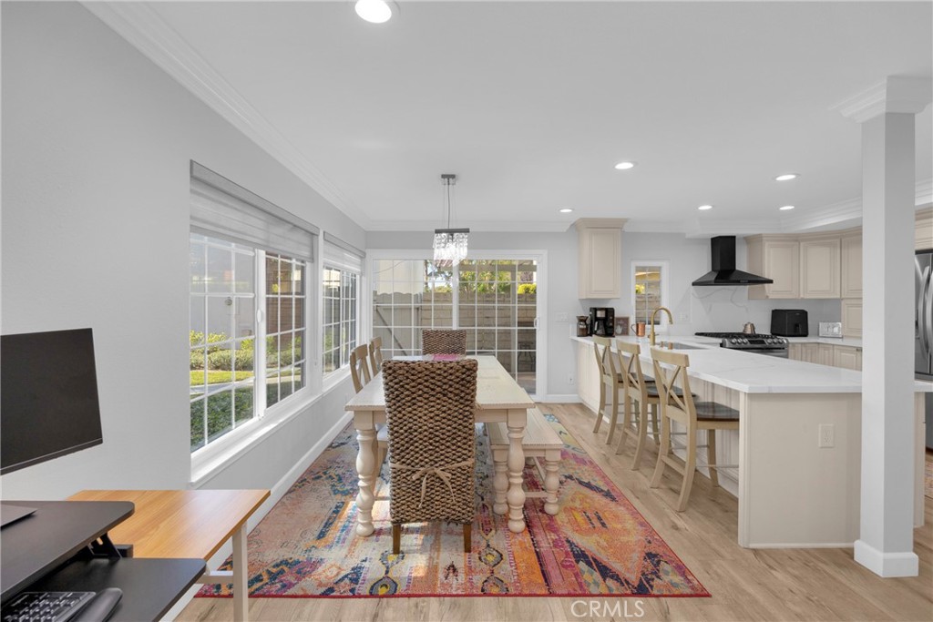 Dining room with a colorful patterned rug beside an open kitchen and large windows.