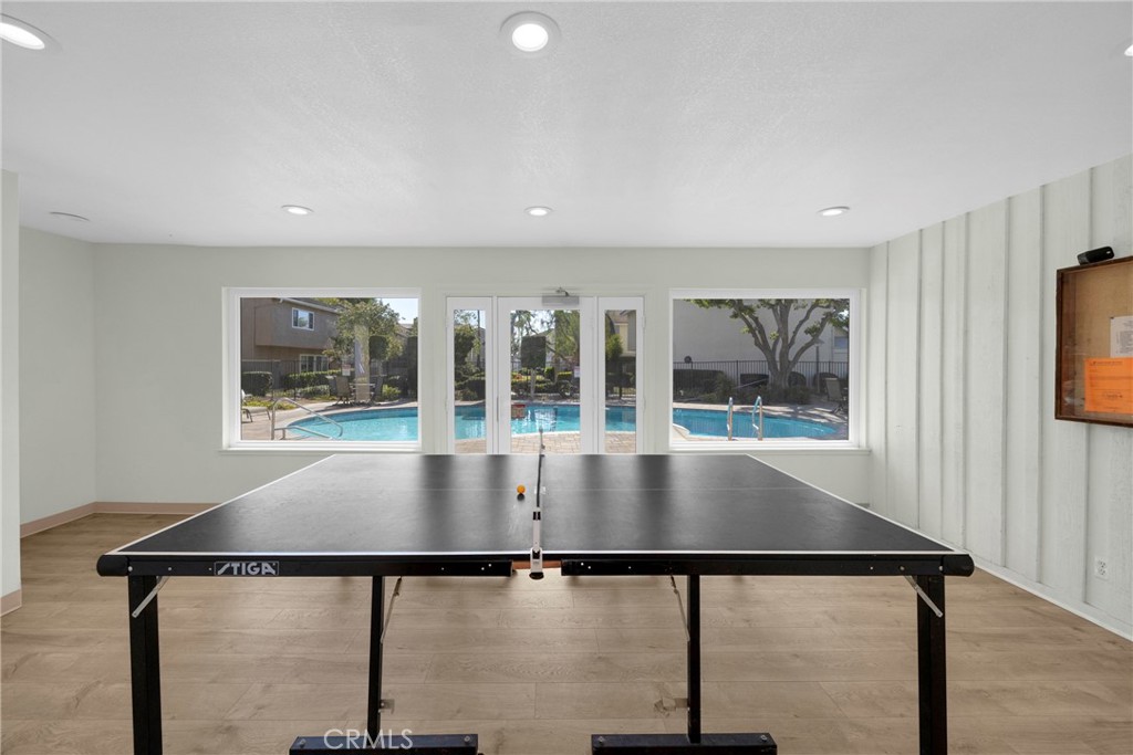 Recreation room with a table tennis table and windows overlooking an outdoor pool.