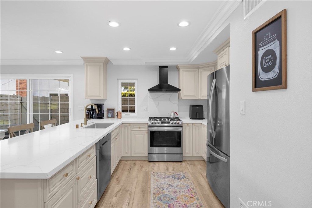 Bright kitchen with white cabinetry, marble-look counters, stainless appliances, and a gas range.