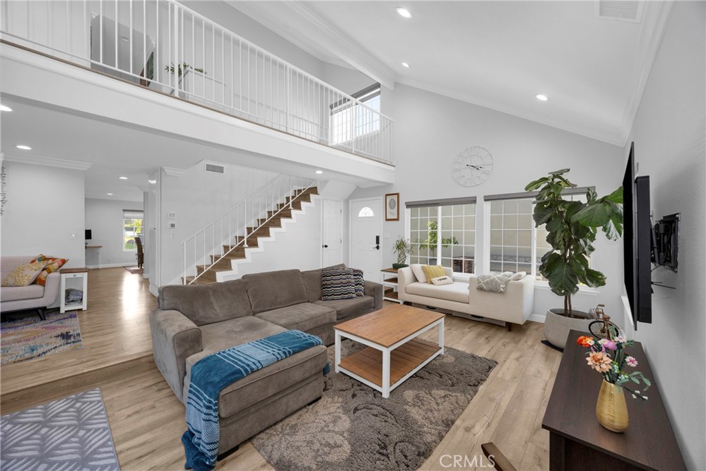 Living room with a vaulted ceiling, open mezzanine, staircase, and gray sectional sofa.
