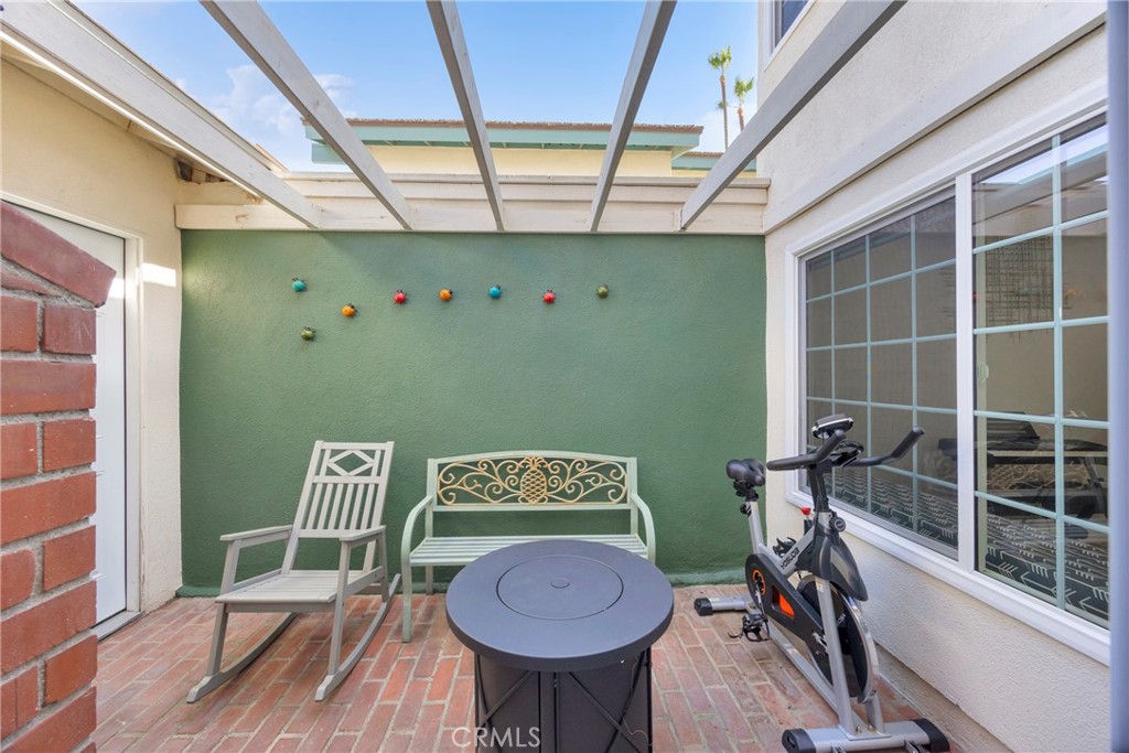 Patio with pergola beams, white seating, a round table, and an exercise bike.