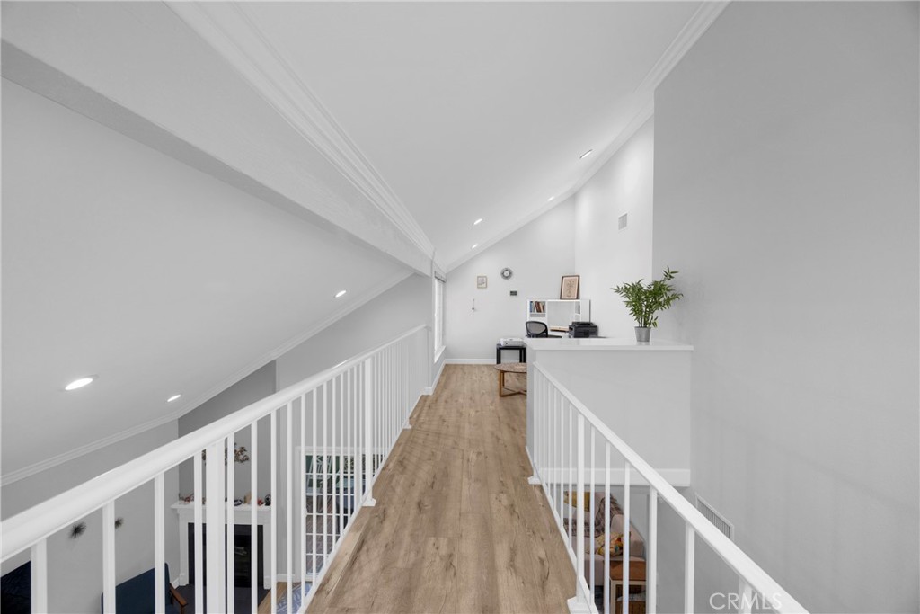 Upstairs loft walkway with wood flooring, white railings, and a small desk nook.