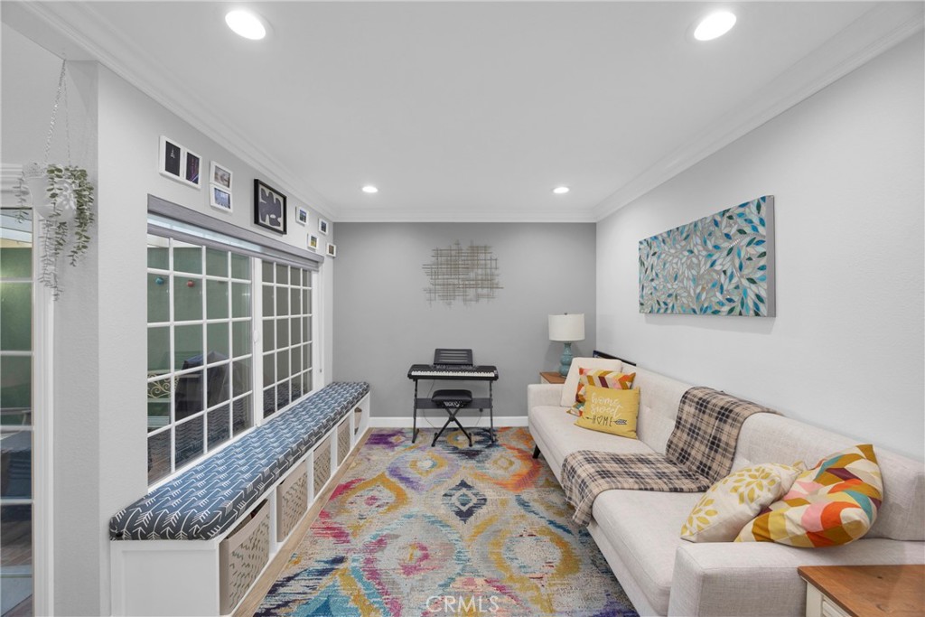 Living room with a cream sofa, colorful rug, keyboard, and window bench.