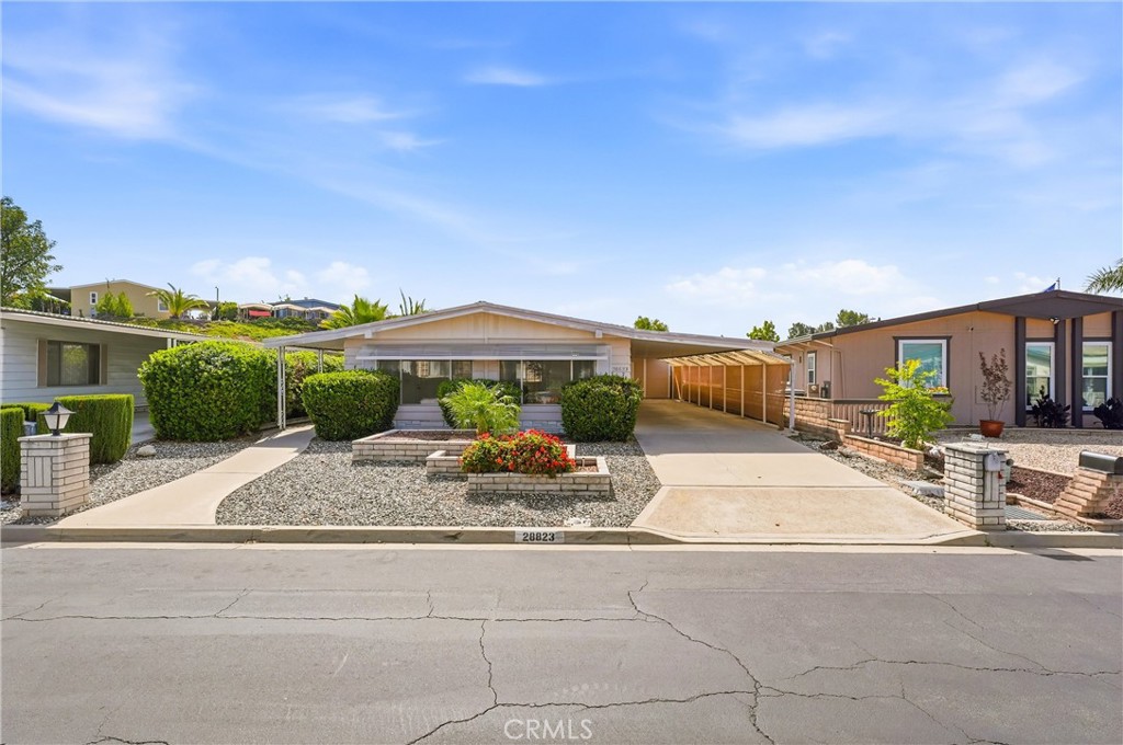 Single-story home with a covered carport, gravel landscaping, and a flower planter.