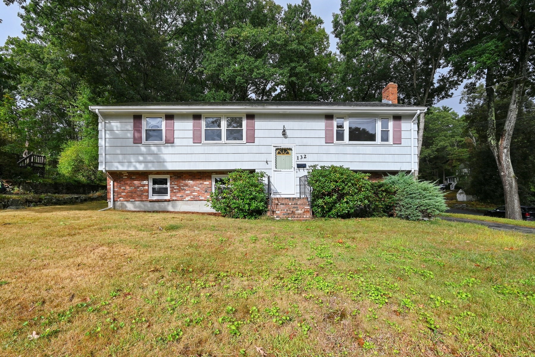 Raised ranch house with white siding, brick lower level, and front steps at 132.