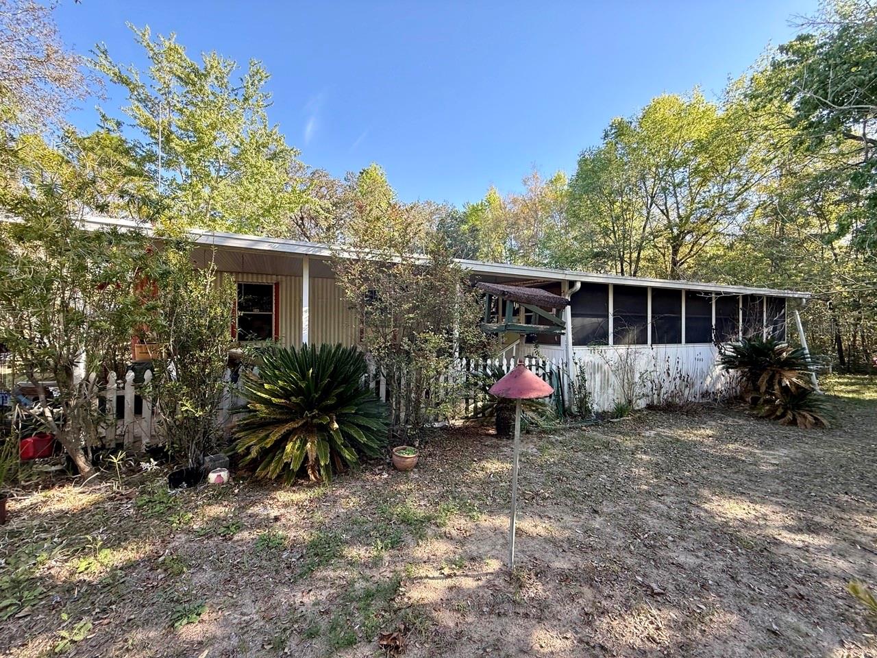 Single-story home with a screened porch, surrounded by trees and shrubs.