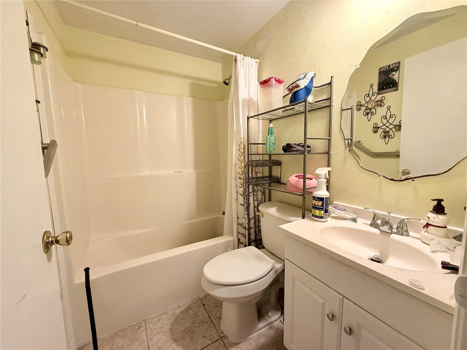 Bathroom with a white tub and shower, toilet, and vanity with a large mirrored cabinet.