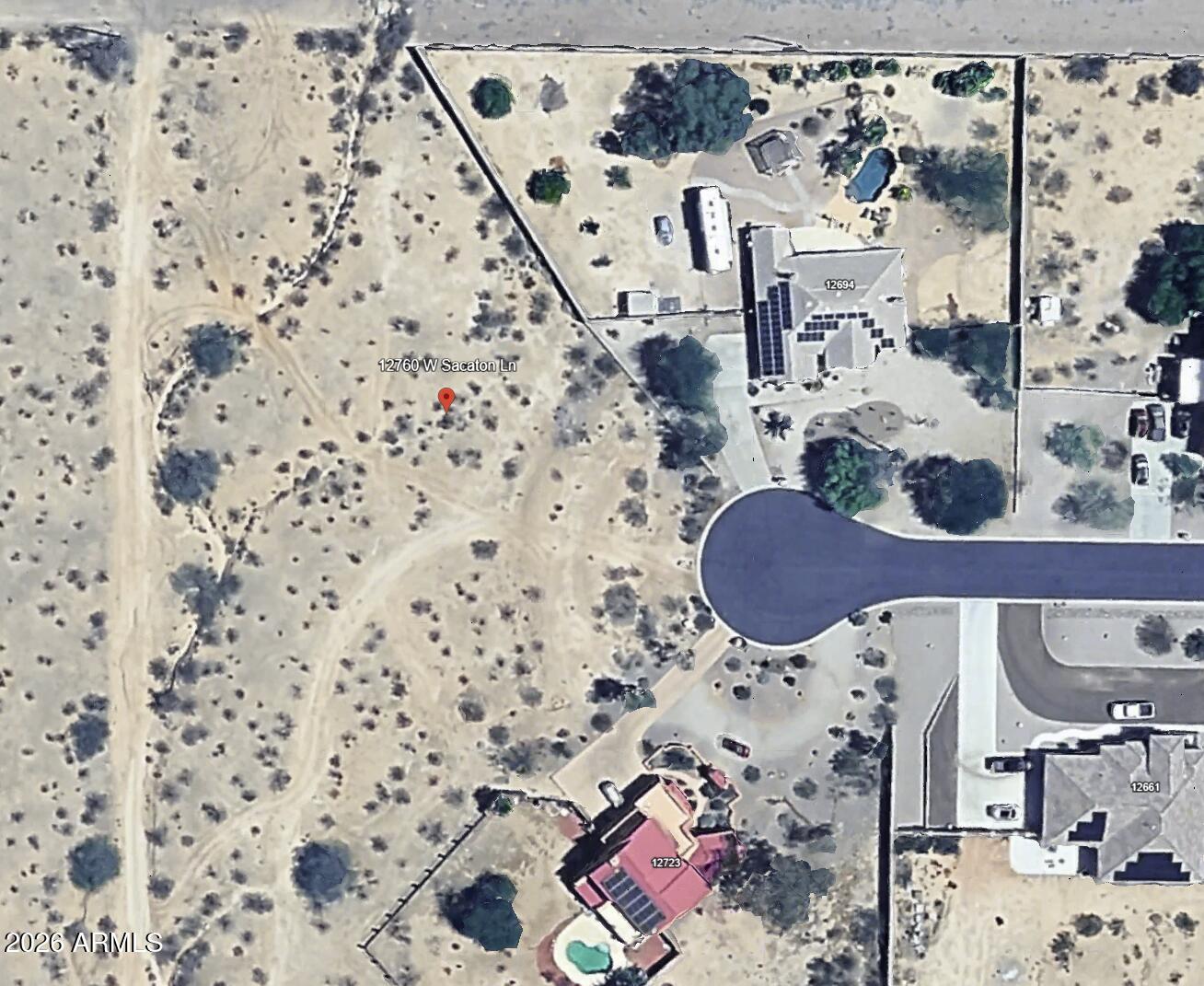 Aerial view of a vacant desert lot beside homes and a residential cul-de-sac.