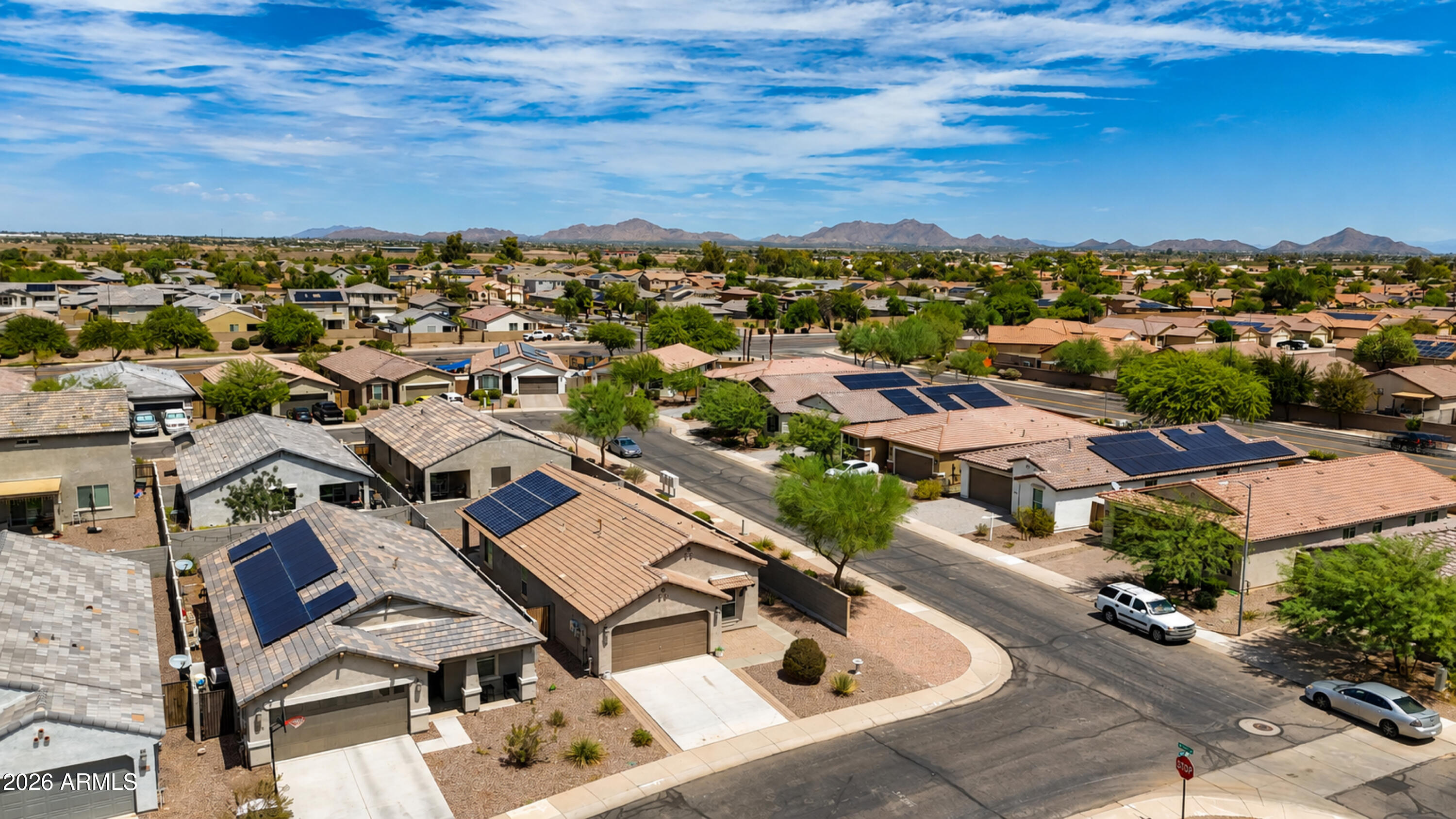 Aerial view of a desert neighborhood with solar-panel roofs and distant mountains.