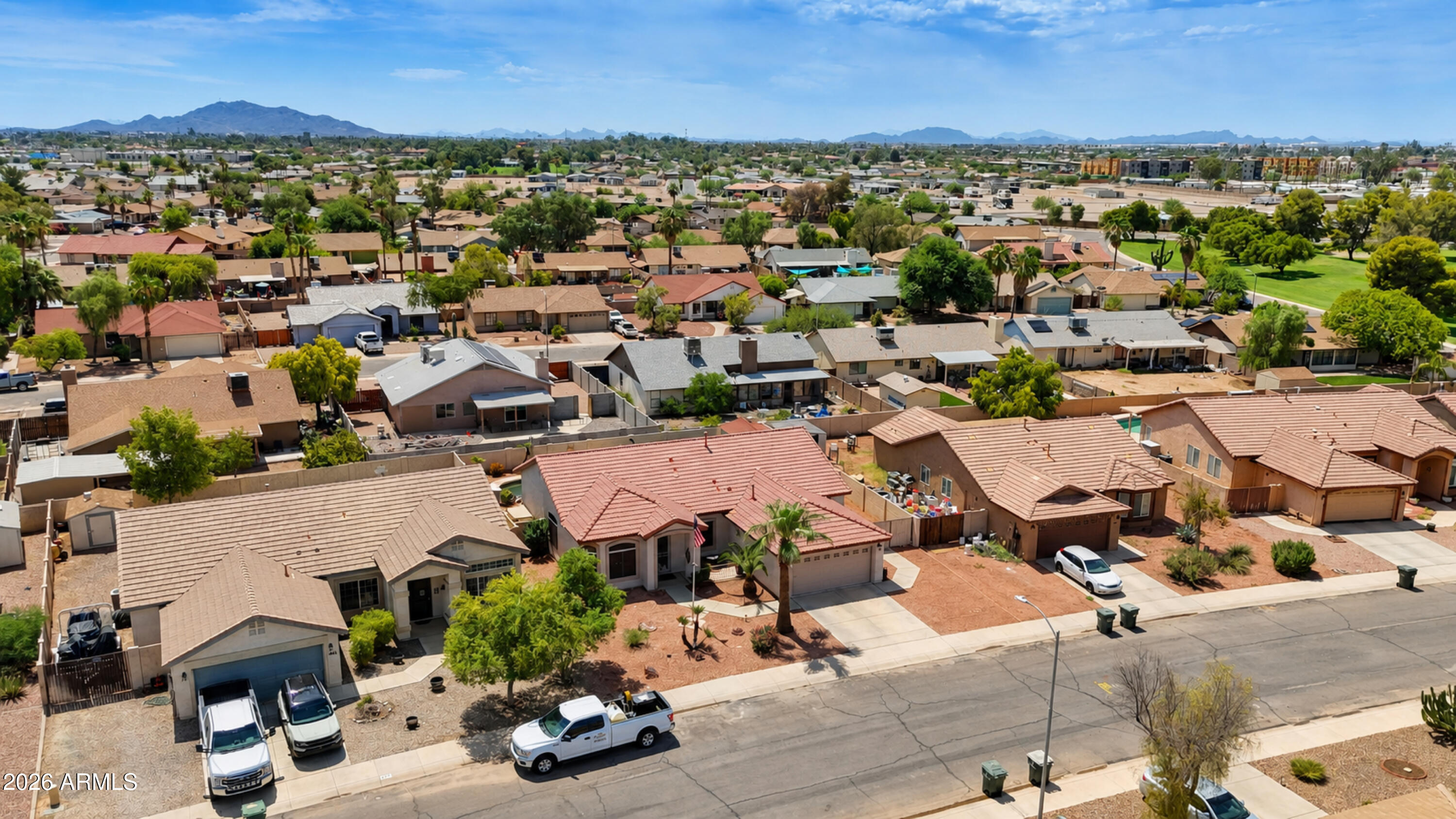 Aerial view of a Casa Grande neighborhood, with a reddish-roofed home in front of distant mountains.