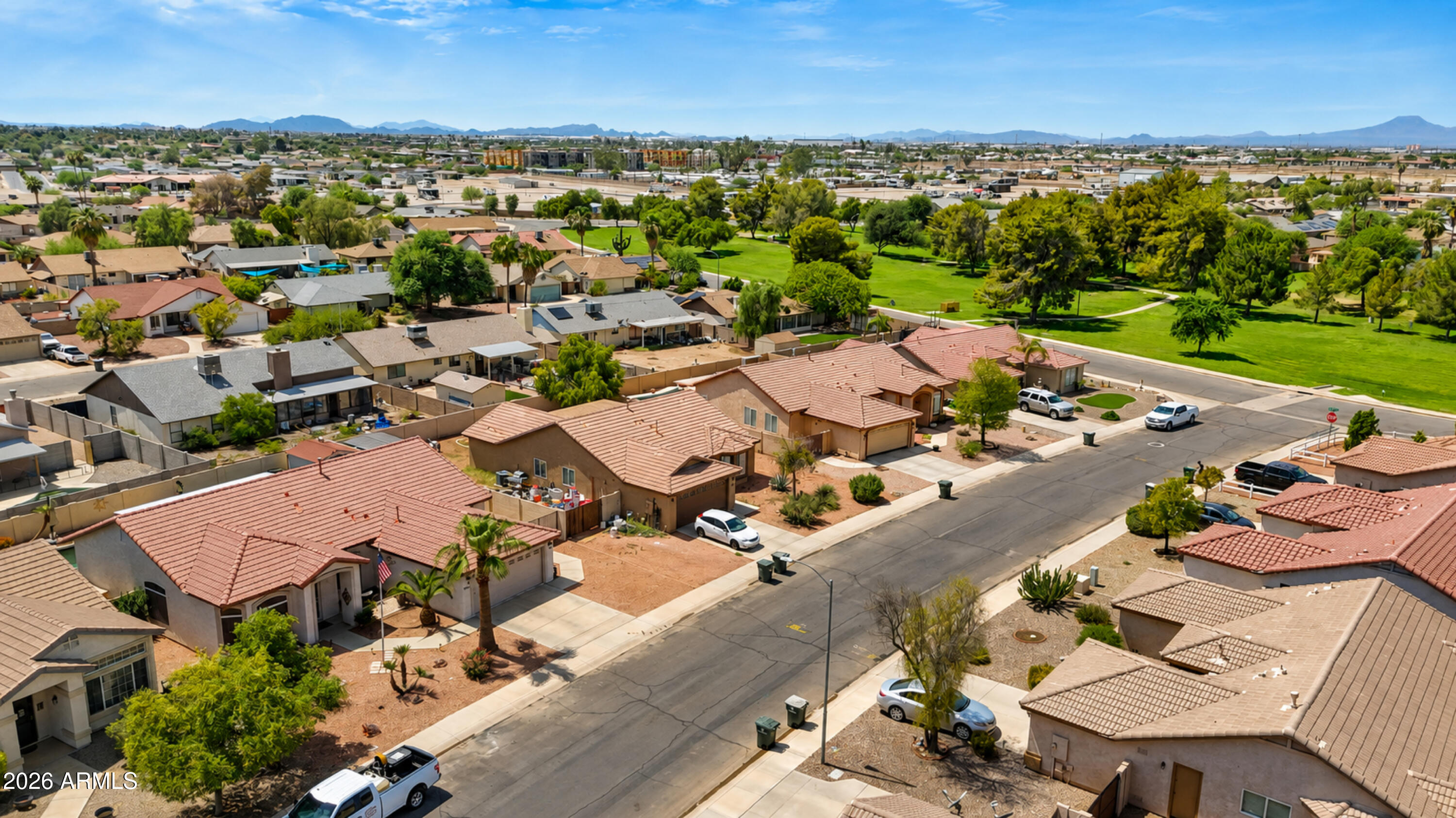 Aerial view of a Casa Grande neighborhood, with a green park and mountains beyond.