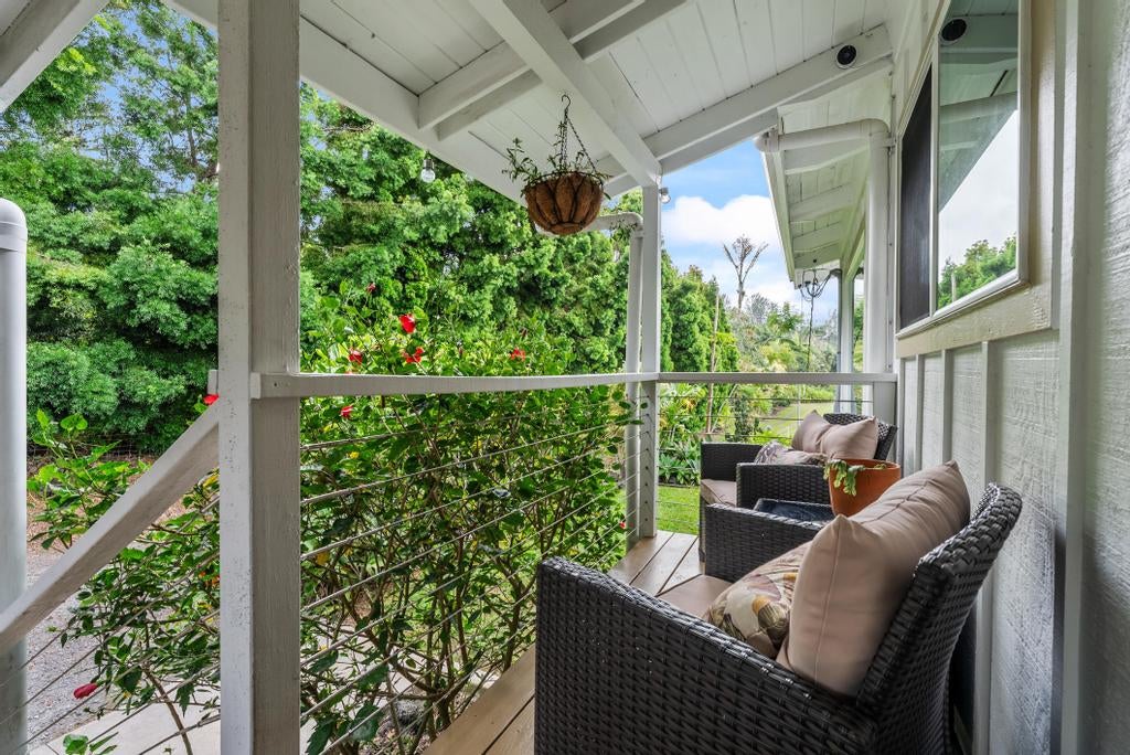 Covered porch with wicker seating and a view of lush tropical greenery.