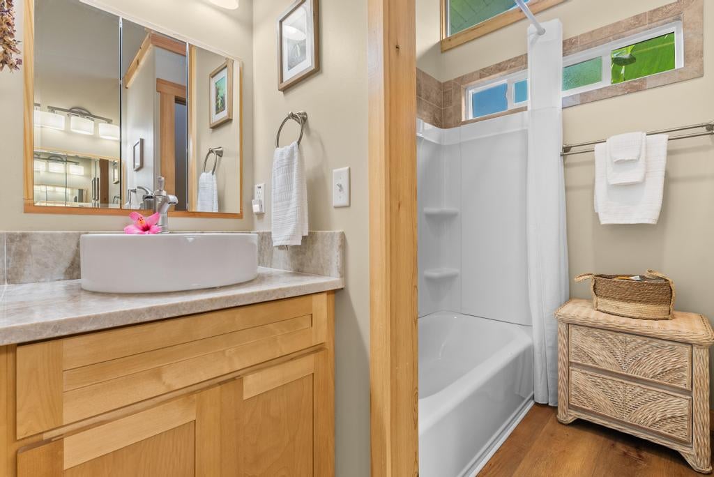 Bathroom with a wood vanity and vessel sink beside a white tub and shower.