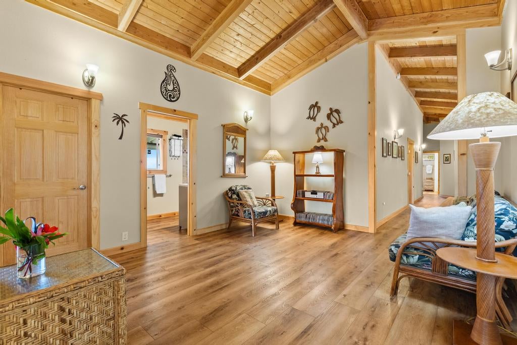 Living room with a vaulted wood ceiling, wicker seating, and wood floors.