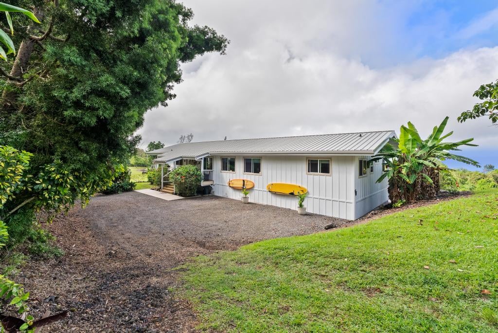 Single-story home with a metal roof, two yellow kayaks, and tropical landscaping.