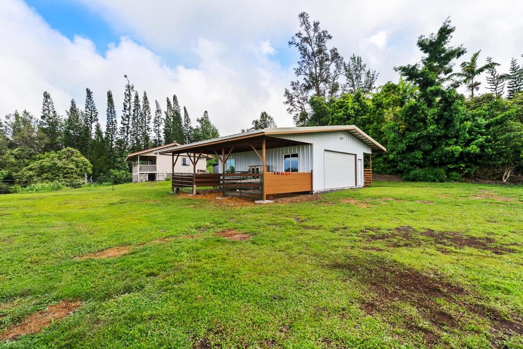 Single-story home with a wide covered porch and garage, set in a grassy yard among trees.