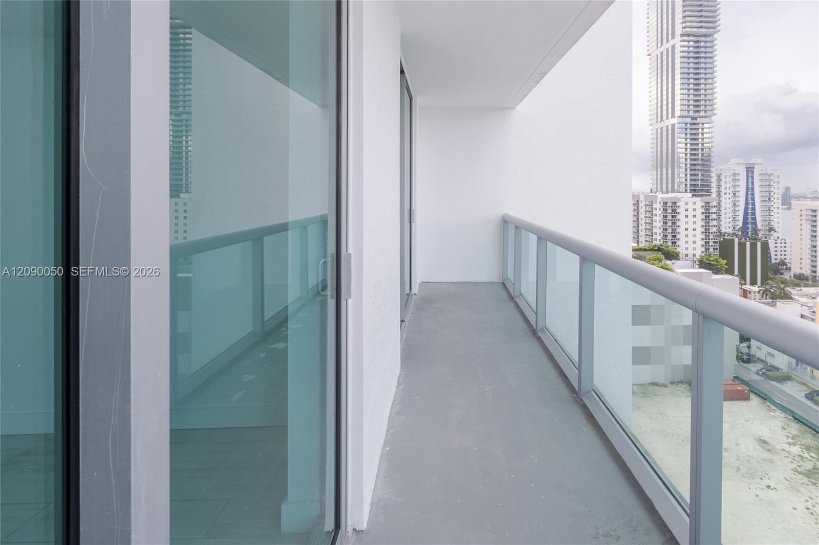 Unfurnished high-rise balcony with glass railing overlooking Miami towers.