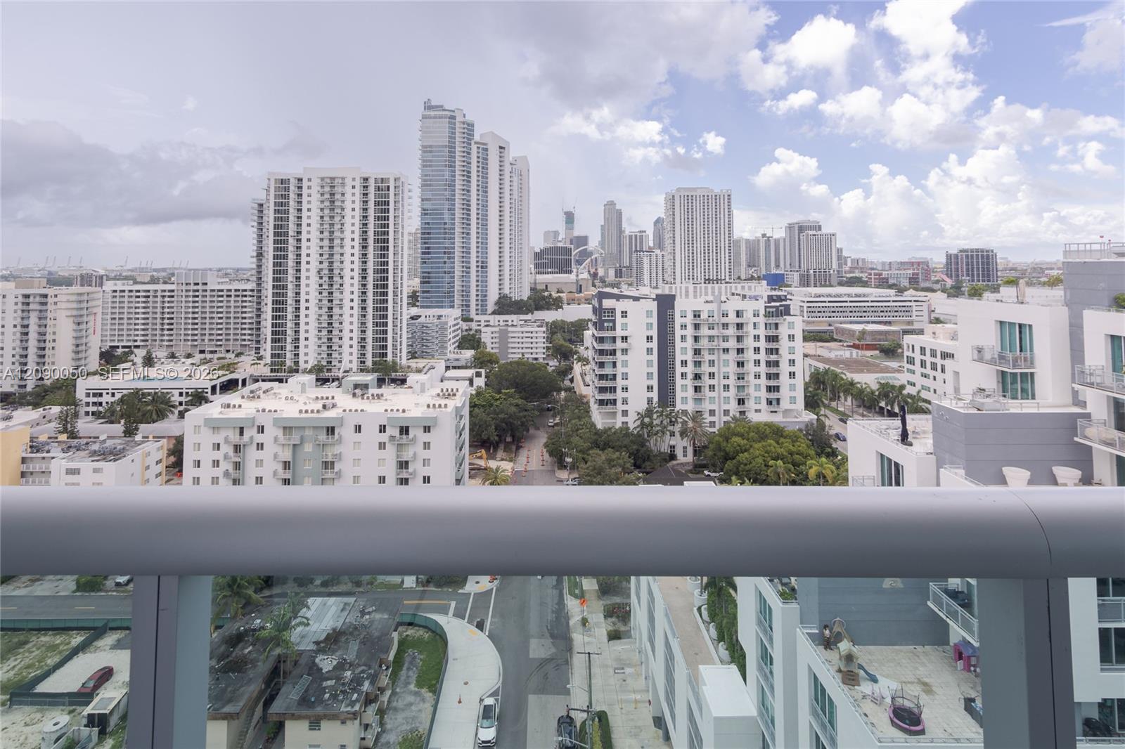 Elevated city view from a balcony, with Miami high-rises beneath a cloudy sky.