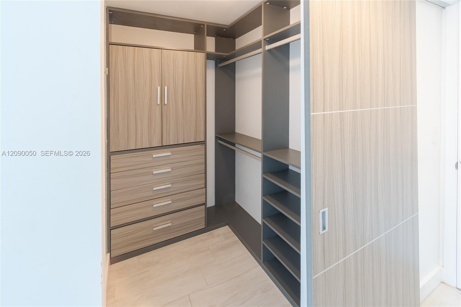 Walk-in closet with built-in wood drawers, open shelving, hanging space, and a sliding door.