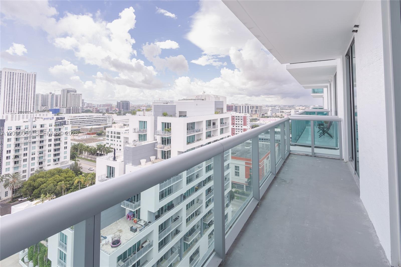 High-rise balcony with glass railing and a wide view of Miami’s surrounding buildings.