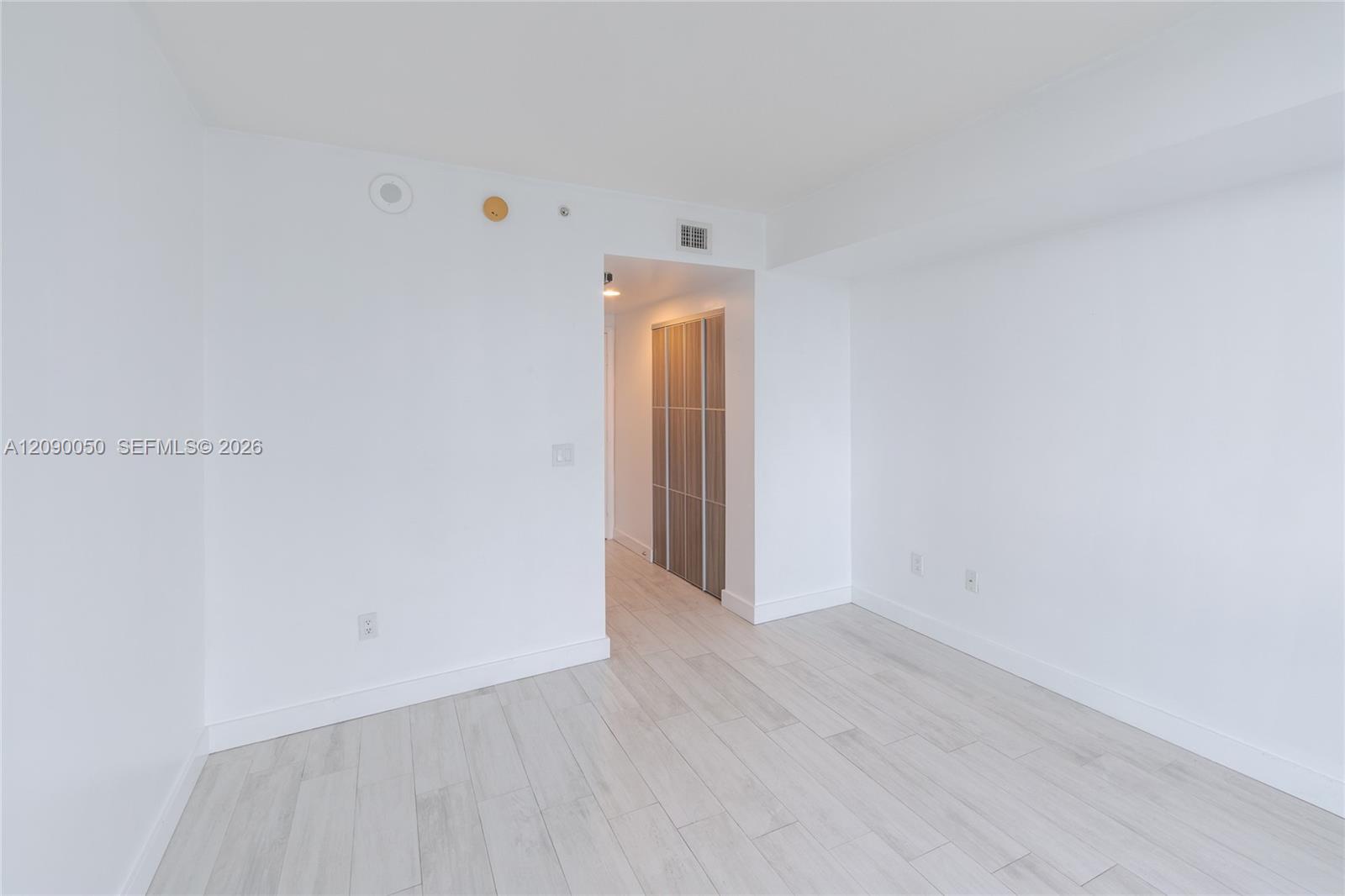 Empty bright room with pale tile flooring and a sliding closet door.