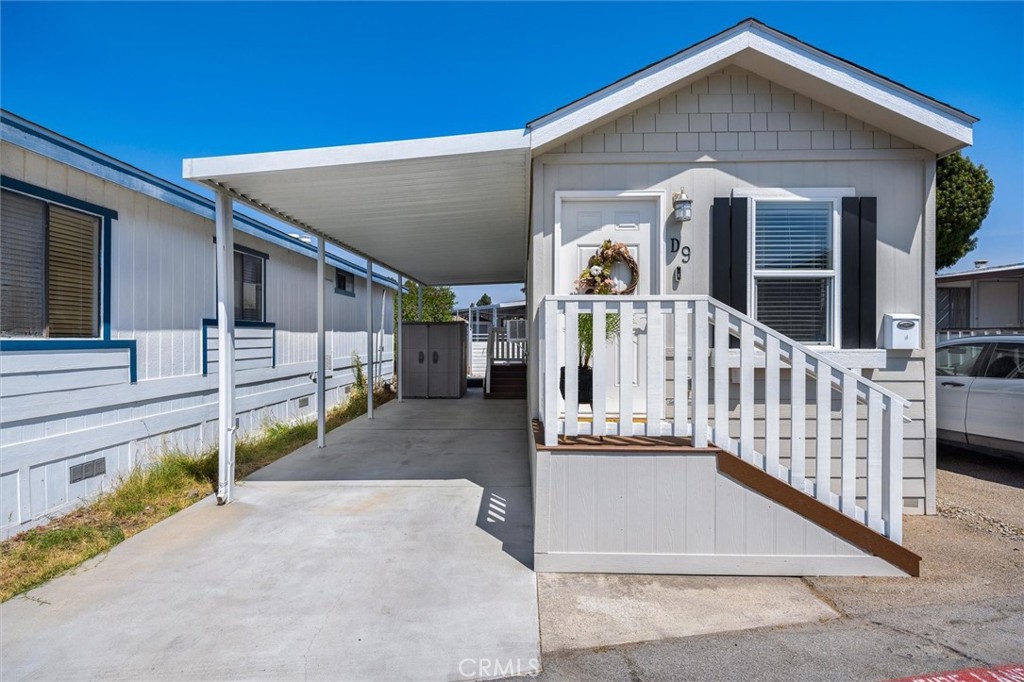 Small white home with a covered carport and white-railed entry ramp beside the front porch.