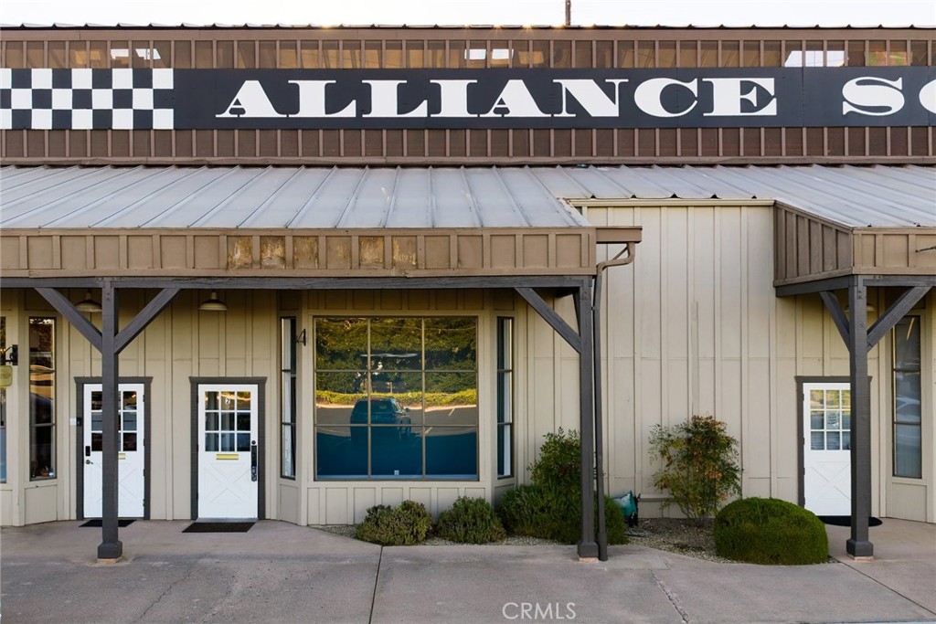Commercial storefront with a covered walkway, several entrances, and an Alliance sign.