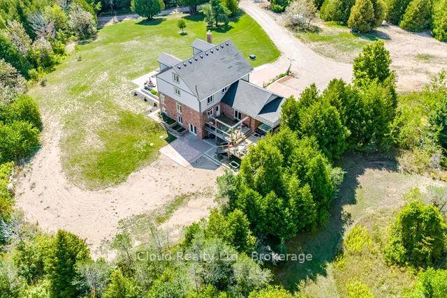 Aerial view of a two-story brick-and-siding house surrounded by trees and open yard.