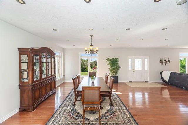 Dining room with a wooden table on a patterned rug, china cabinet, and polished hardwood floors.