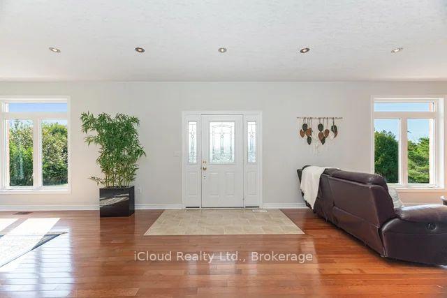 Living room with a white front door, polished hardwood floors, and a dark sectional sofa.
