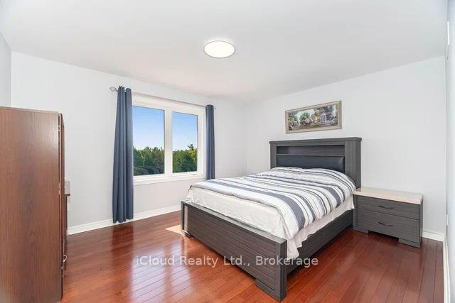 Bedroom with striped bedding, dark wood furniture, polished hardwood floors, and a window overlooking trees.