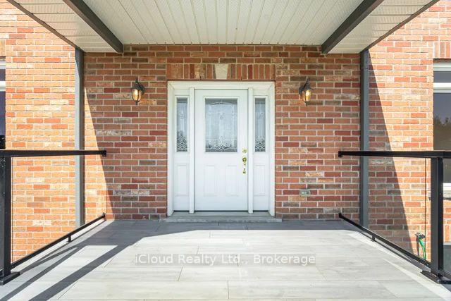 Brick home entrance with a covered porch, white double doors, and black railings.