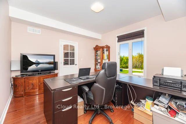 Home office with dark desks, a leather chair, and a large window overlooking greenery.