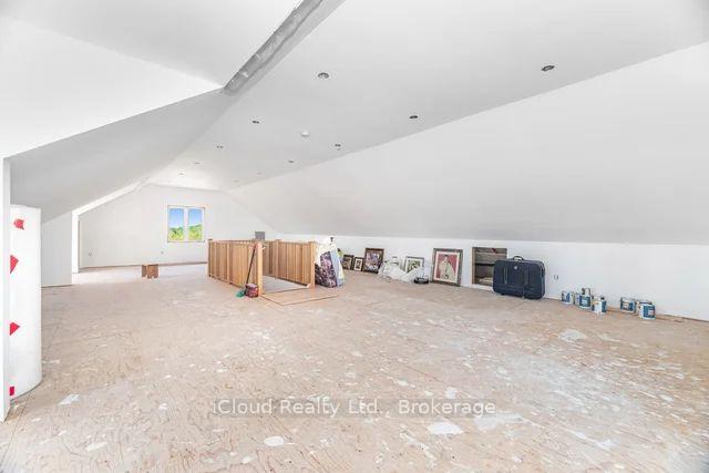 Unfinished attic with a sloped ceiling, small window, and wooden railing around an opening.