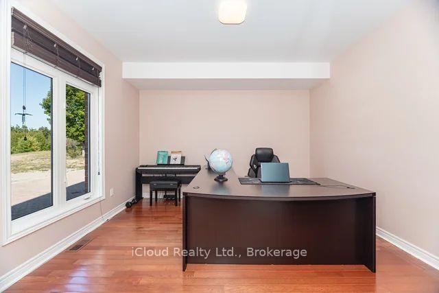 Home office with a curved desk, globe, and digital piano beside large glass doors.