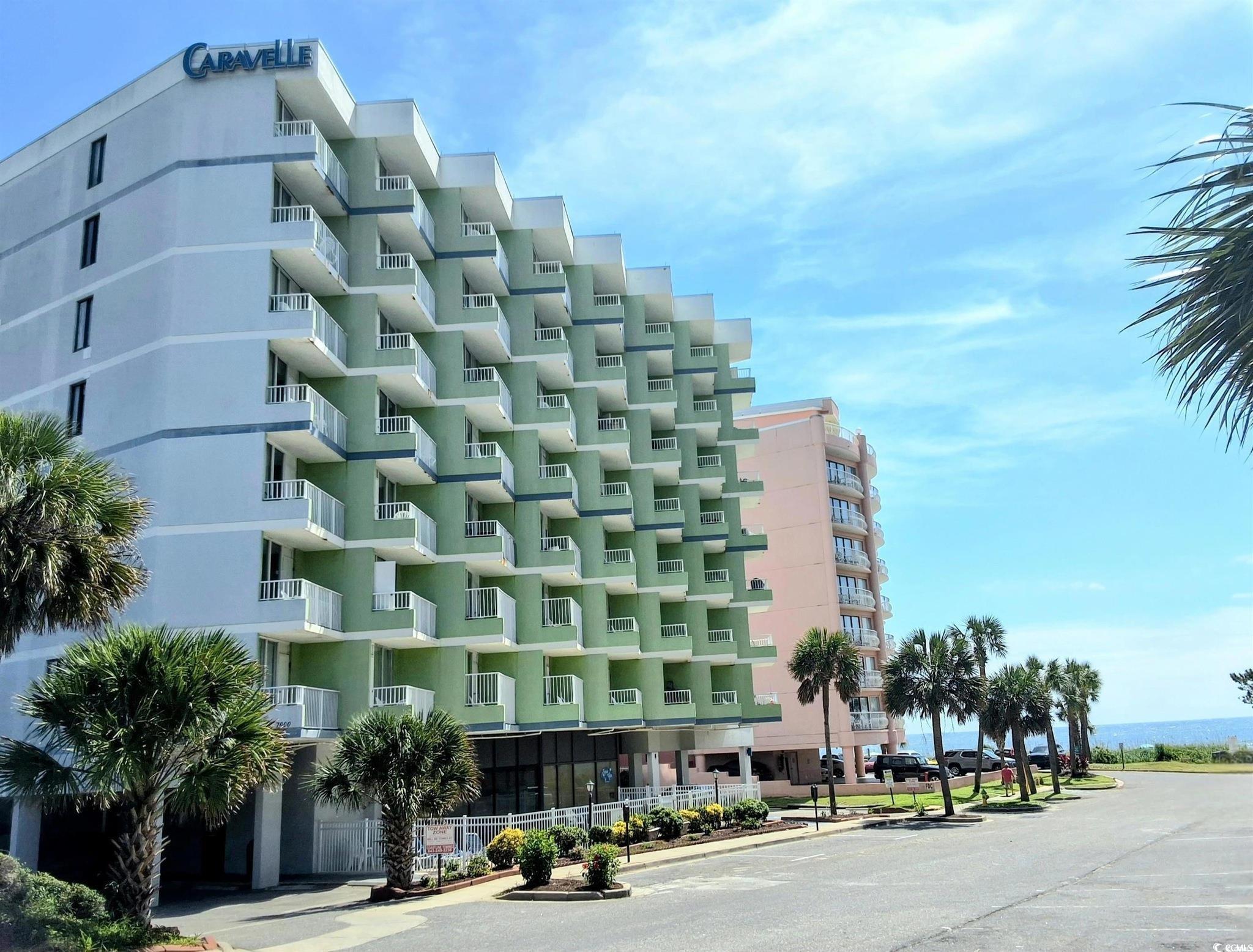 Caravelle oceanfront condominium with staggered balconies, palm trees, and ocean view.
