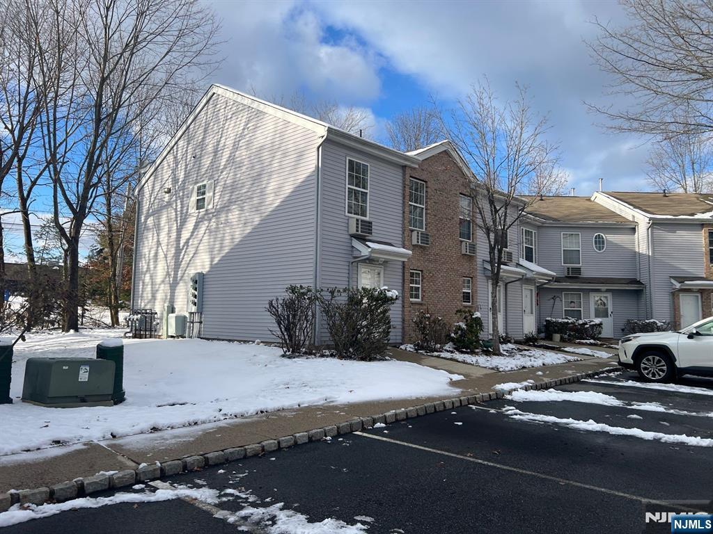 Attached gray-sided townhouse with a brick facade beside a snow-covered sidewalk.