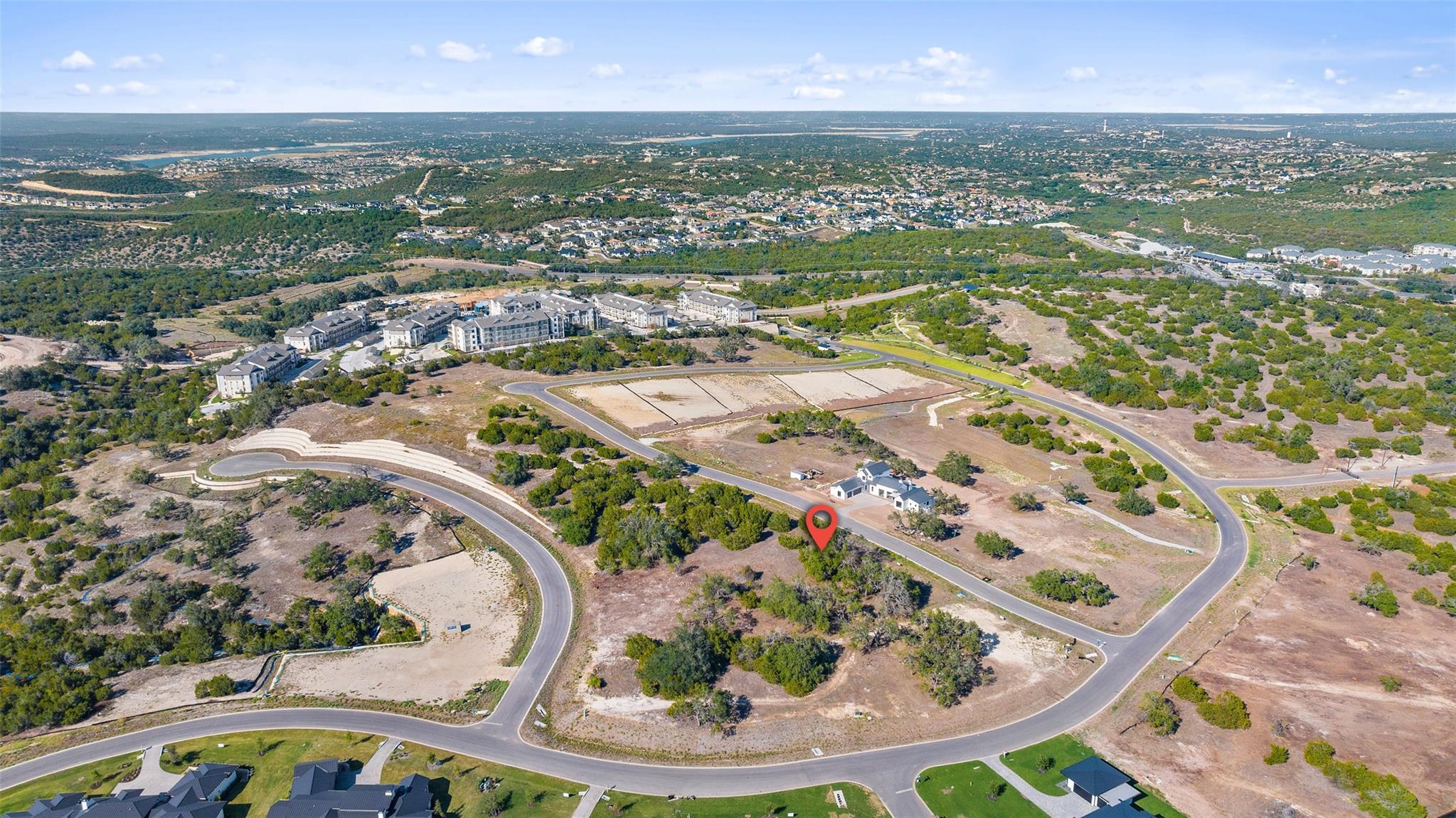 Aerial view of a vacant lot marked by a red pin among subdivision roads and homes.