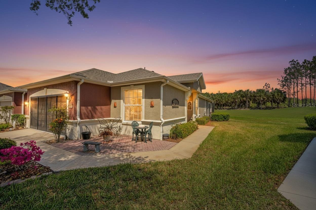 Single-story stucco home with a screened patio and outdoor seating at dusk.