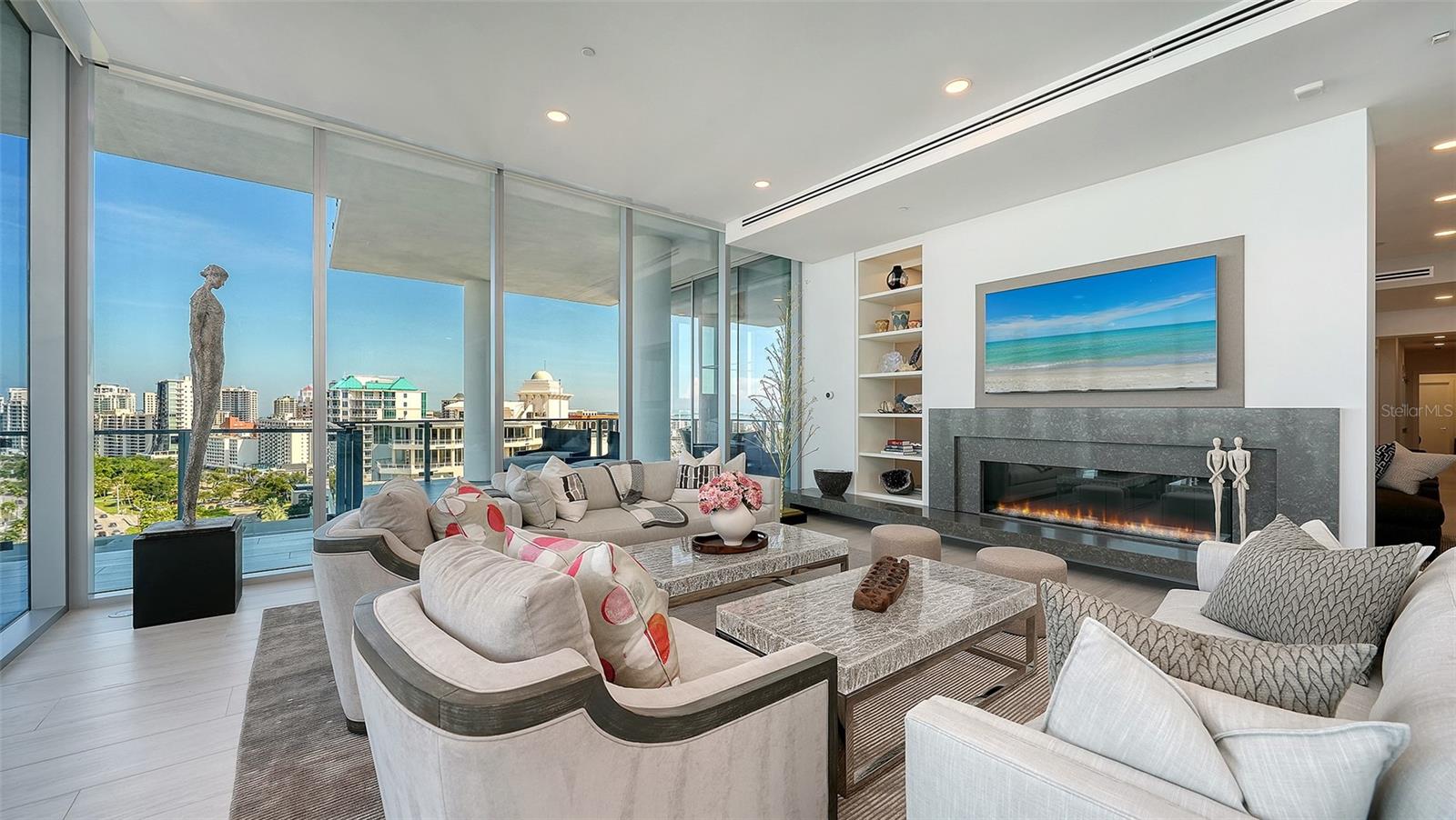 High-rise condo living room with floor-to-ceiling windows, curved sofas, and a modern fireplace.