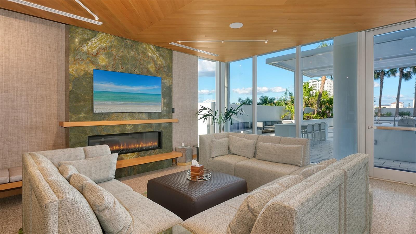 Furnished living room with a stone fireplace, wood ceiling, and glass doors opening to a terrace.