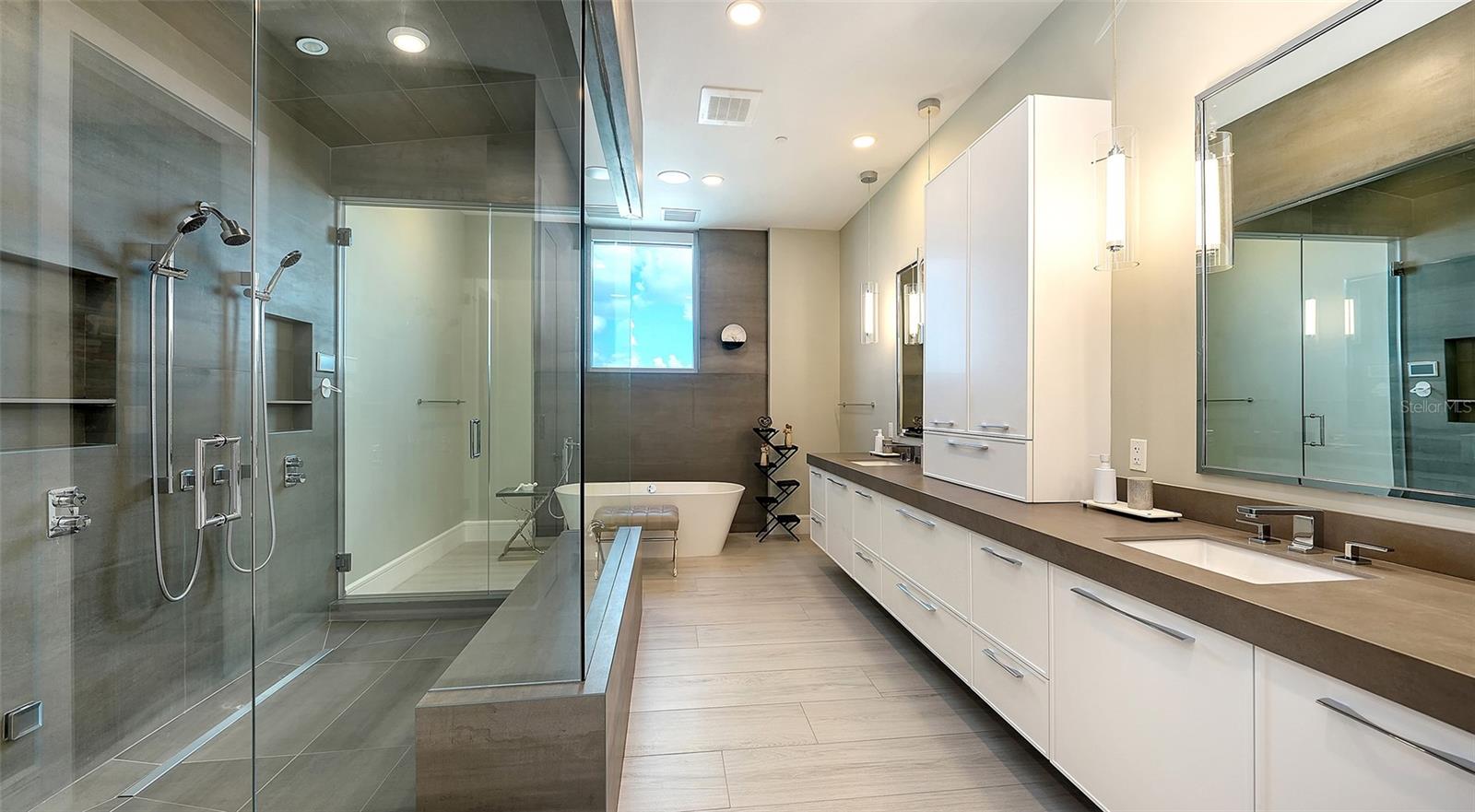 Modern bathroom with glass walk-in shower, freestanding tub, and long white double vanity.